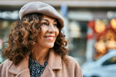 Orta yaşlı İspanyol kadın gülümseyerek şehirde mutlu mesut dikiliyor..