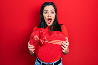 Sevgililer günü hediyesini elinde tutan genç İspanyol kız şaşkınlık ve şaşkınlık dolu bir ifade, korku ve heyecan dolu bir yüz.. 