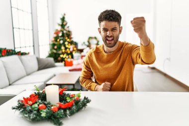 Arap genç adam, kızgın ve kızgın bir şekilde masada oturmuş öfkeyle bağırırken yumruğunu kaldırıyor. öfke ve agresif konsept. 