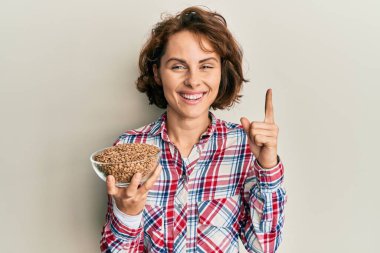 Genç esmer kadın elinde mercimeği fırına verip gülümsüyor. 