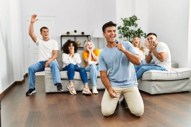 Bir grup genç arkadaş evde mikrofon kullanarak şarkı söylüyor..