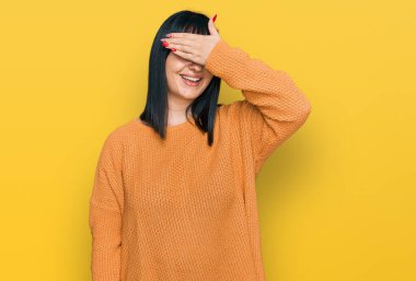 Gündelik kıyafetler giyen, gülümseyen ve gülümseyen genç İspanyol kadın şaşırmak için gözlerini kapatıyor. kör kavram. 