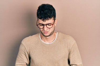 Genç İspanyol adam günlük kıyafetler giyiyor ve elleri karnında gözlük takıyor çünkü hazımsızlık, acı verici bir hastalık kendini iyi hissetmiyor. Ağrı kavramı. 