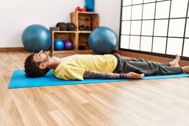 Genç İspanyol adam yerde yatıyor spor merkezinde dinleniyor..