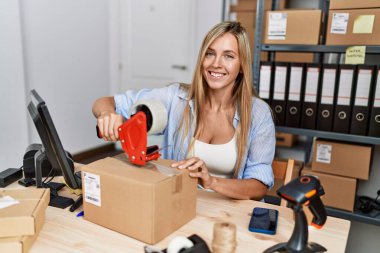 Genç sarışın kadın ecommerce iş işçisi ofiste paket paketleme