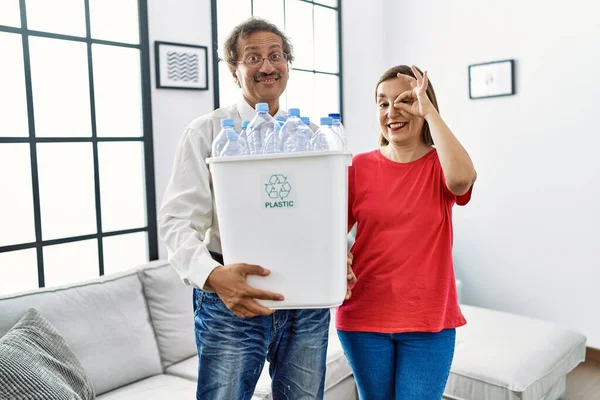 Medelålders Rasblandat Par Som Håller Återvinning Bin Med Plastflaskor Hemma — Stockfoto