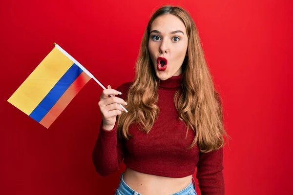 年轻的金发女郎高举哥伦比亚国旗 惊慌失措 张大了嘴 满脸诧异 — 图库照片