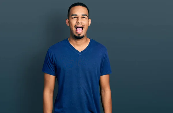 若いアフリカ系アメリカ人の男性が面白い表情で幸せ舌を突き出してカジュアルなTシャツを着ています 感情の概念 — ストック写真