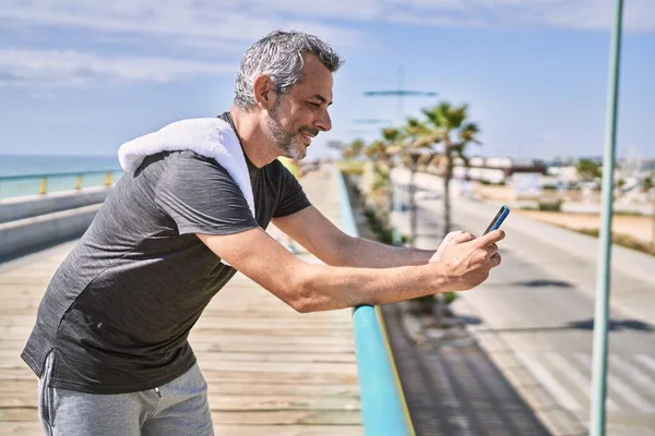 Orta Yaşlı Spanyol Adam Deniz Kenarında Akıllı Telefon Kullanarak Spor — Stok fotoğraf