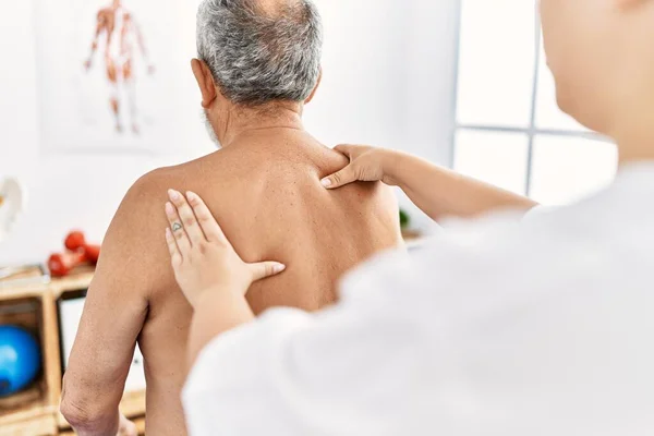 Physiotherapist and patient on back view having rehab session at clinic