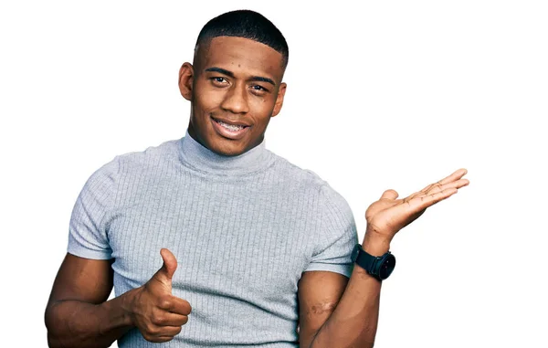若い黒人男性を着てカジュアルなTシャツを示すヤシの手と親指で をジェスチャーを行います 笑顔幸せと陽気な — ストック写真