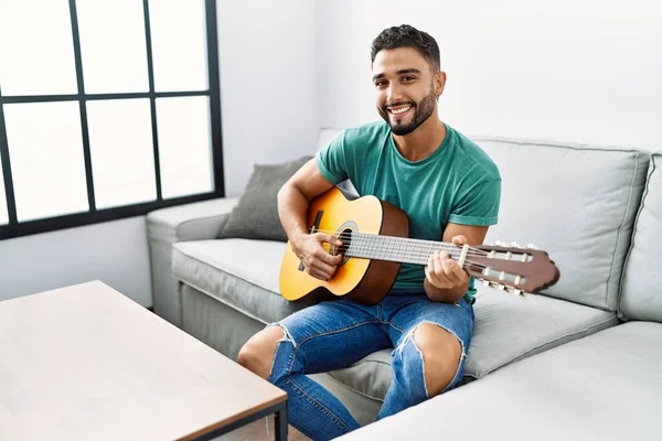 Jonge Arabisch Man Speelt Klassieke Gitaar Zittend Bank Thuis — Stockfoto