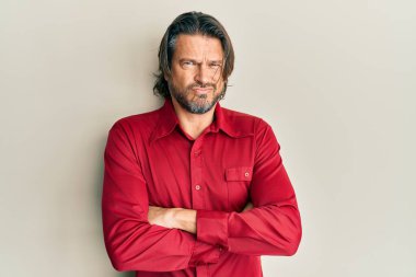 Orta yaşlı, sıradan kıyafetler giyen, kuşkucu ve gergin, yüzünde çapraz kollu tasvip etmeyen bir ifade olan yakışıklı adam. negatif kişi. 