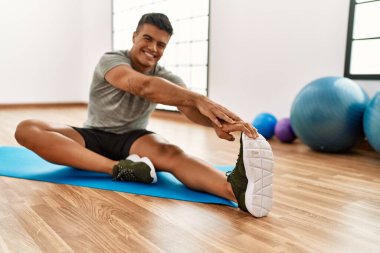 Genç İspanyol adam gülümsüyor spor merkezinde esniyor.