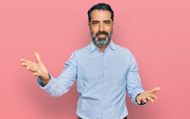 Orta yaşlı, sakallı, iş gömleği giyen, gülümseyen, yardım eli uzatan ve kabul gören bir adam.. 