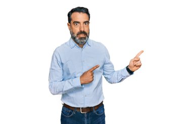 Orta yaşlı, sakallı, iş gömleği giyen, endişeli ve gergin bir adamı iki eliyle gösteren, endişeli ve şaşırmış bir ifade. 