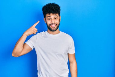 Sakallı, beyaz tişörtlü genç bir Arap tek parmağıyla başını gösteren harika bir fikir ya da düşünce, iyi bir hafıza. 