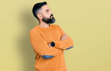 Sakallı, sıradan bir süveter giyen İspanyol adam kollarını kavuşturmuş, ikna olmuş ve kendinden emin bir şekilde yan tarafa bakıyor. 