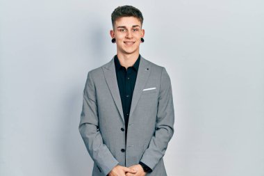 Kulakları genişlemiş, iş ceketi giymiş, yüzünde mutlu ve havalı bir gülümseme olan beyaz bir çocuk. şanslı kişi. 