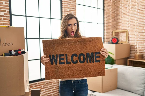 Young Woman Holding Welcome Doormat New Home Shock Face Looking — Fotografia de Stock