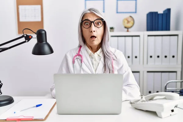 Średniowieczna Siwowłosa Kobieta Mundurze Lekarza Pracująca Pomocą Laptopa Komputerowego Przerażona — Zdjęcie stockowe