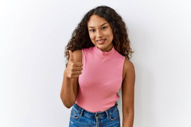 Güzel İspanyol kadın izole edilmiş arka planda duruyor ve elleriyle mutlu bir jest yapıyor. Kameraya bakıp başarıyı gösteren ifade. 
