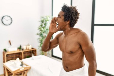 Genç Afrikalı Amerikalı üstsüz bir adam güzellik merkezinde el ele tutuşarak bağırıyor ve bağırıyor. iletişim konsepti. 