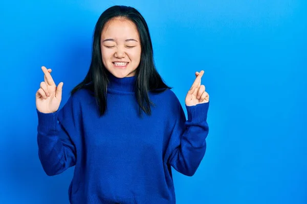若い中国の少女は 希望と目を閉じて笑顔を渡った指をジェスチャーカジュアルな服を着て 幸運と迷信の概念は — ストック写真