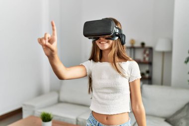 Evde video oyunu oynayan sevimli bir kız VR gözlük kullanıyor.