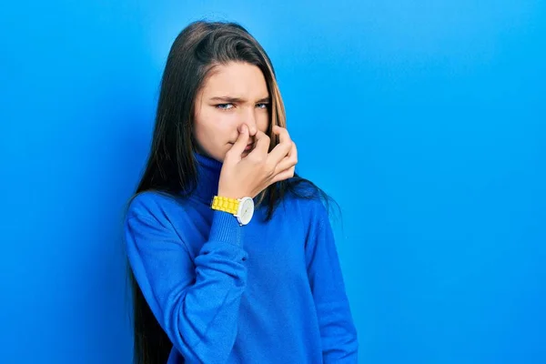 若いブルネットの女の子は 鼻の上に指で息を保持し 臭いと嫌な 耐え難い匂いを嗅ぐタートルネックセーターを着ています 臭いが悪い — ストック写真