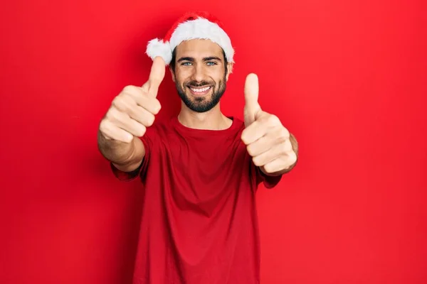 Noel Şapkası Takan Spanyol Genç Adam Elinle Olumlu Jest Yapmayı — Stok fotoğraf
