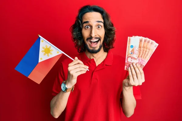 Young Hispanic Man Holding Philippines Flag Pesos Banknotes Celebrating Crazy — Stock Photo, Image