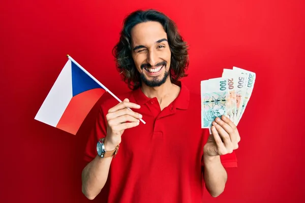 Joven Hombre Hispano Sosteniendo Bandera República Checa Billetes Corea Guiñando —  Fotos de Stock