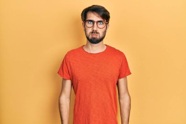 Günlük kıyafetler giyen, gözlüklü, komik yüzlü, yanak şişiren genç İspanyol bir adam. Havayla şişmiş ağız, çılgın bir ifade.. 