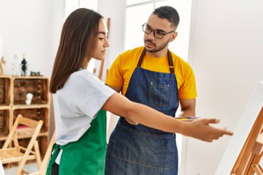 Resim atölyesinde resim çizen öğrenciye benzeyen ciddi ifadeli genç bir resim öğretmeni..