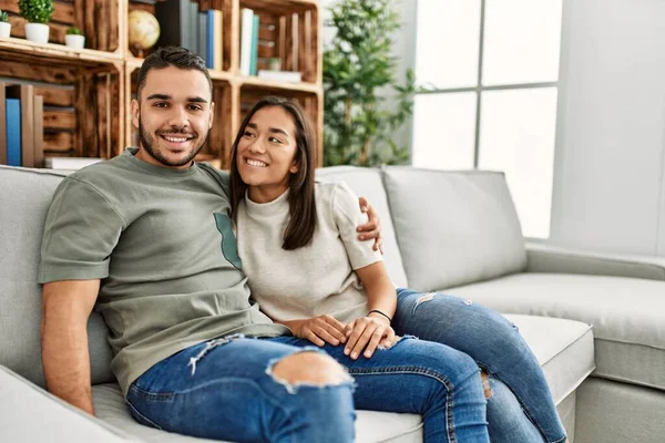 Jovem Casal Latino Sentado Sofá Abraçando Casa — Fotografia de Stock