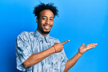 Sakallı genç Afrikalı Amerikalı adam kameraya hayret ediyor ve gülümsüyor.. 