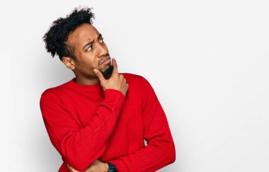 Sakallı, kışlık süveter giyen genç Afrikalı Amerikalı bir adam bir soru hakkında endişeli ve gergin bir şekilde düşünüyor. 