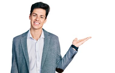 İş kıyafetleri giymiş, neşeli gülümseyen, eli avucunda kameraya bakan genç İspanyol bir adam.. 