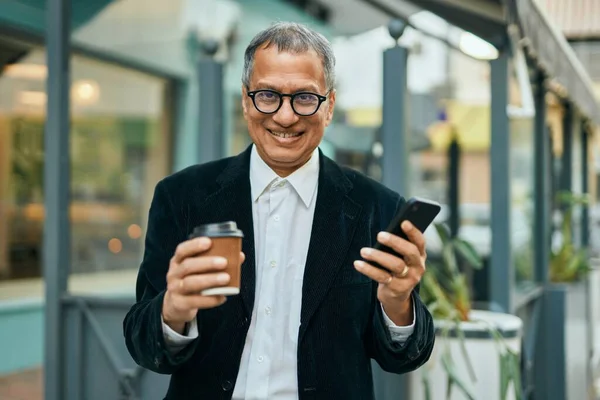 동남아시아의 남자가 스마트폰으로 웃으며 도시에서 커피를 마시고 있습니다 — 스톡 사진