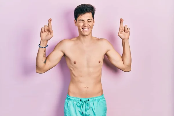 Young Hispanic Man Wearing Swimwear Shirtless Gesturing Finger Crossed Smiling — Stock Photo, Image