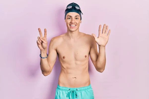 身穿泳衣 戴着泳镜的年轻人 戴着七号手指 面带微笑 自信而快乐 — 图库照片