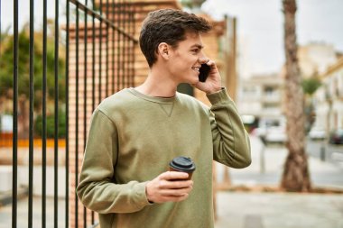 Genç İspanyol adam akıllı telefondan konuşuyor. Şehirde kahve içiyor..