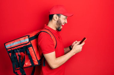 Sırt çantası takan İspanyol bir adam akıllı telefon kullanıyor ve kahkahalarla gülüyor.. 