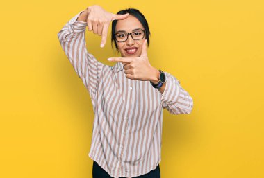 Gündelik kıyafetler ve gözlük takan, gülümseyen, elleri ve parmakları gülen yüzlü genç İspanyol kız. yaratıcılık ve fotoğrafçılık kavramı. 