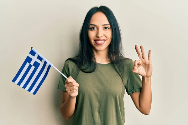 Menina Hispânica Jovem Segurando Bandeira Grega Fazendo Sinal Com Dedos — Fotografia de Stock