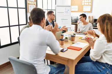 Ofisteki ortağına gülümseyen ve alkışlayan bir grup işçi..