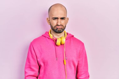 Spor kıyafetleri giyen ve kulaklık takan genç kel bir adam depresif ve endişeli, sinirli ve korkmuş bir halde. hüzünlü ifade. 