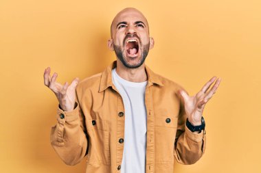 Genç kel adam, gündelik kıyafetler giyip deli gibi bağırıyor ve agresif bir ifade ve kollarla bağırıyor. hüsran kavramı. 