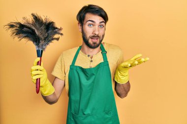 Önlük giyen İspanyol asıllı genç adam başarıyı mutlu bir gülümsemeyle ve elini kaldırarak kutluyor. 